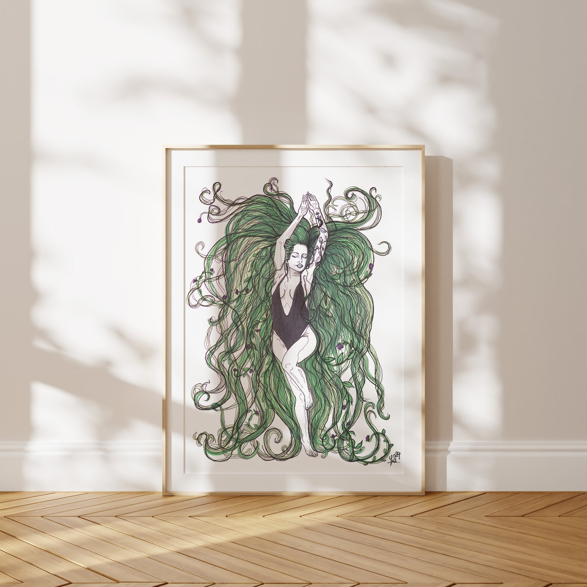 Framed artwork of a woman with flowing green hair on a white wall. A piece on our relationship with Mother Earth.