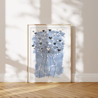 Framed artwork with hands holding hearts against a light blue background on a wooden floor.