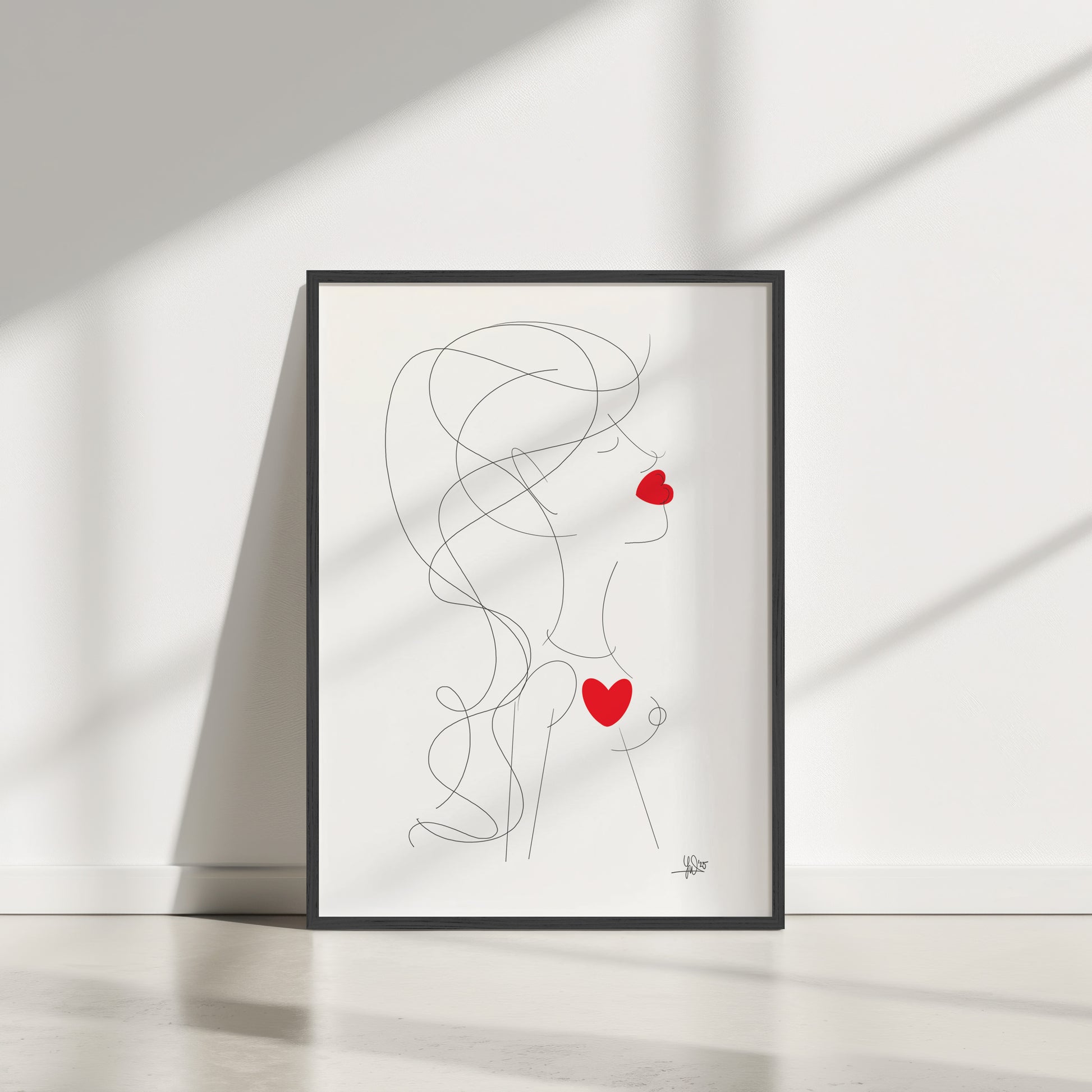 Framed abstract and minimalistic artwork of a woman with red hearts on a white wall.