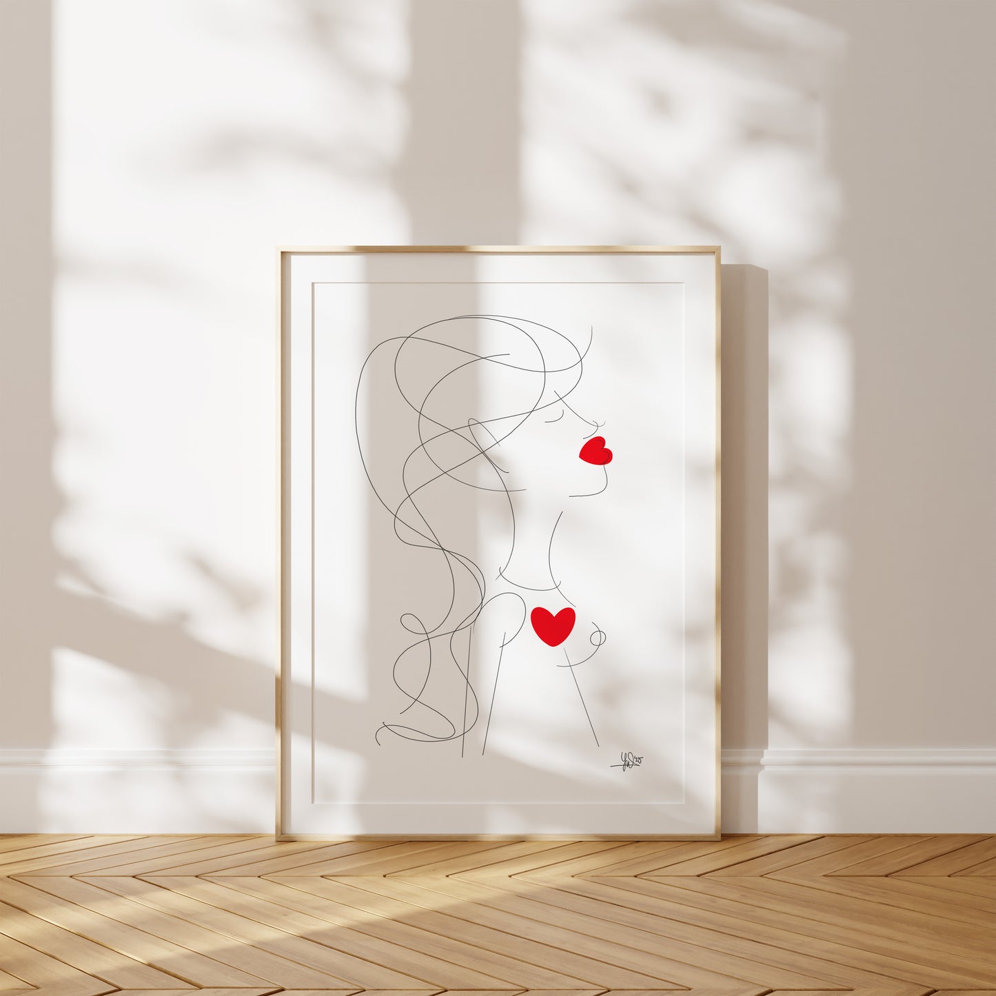 Framed abstract artwork of a woman with red hearts on a white wall.